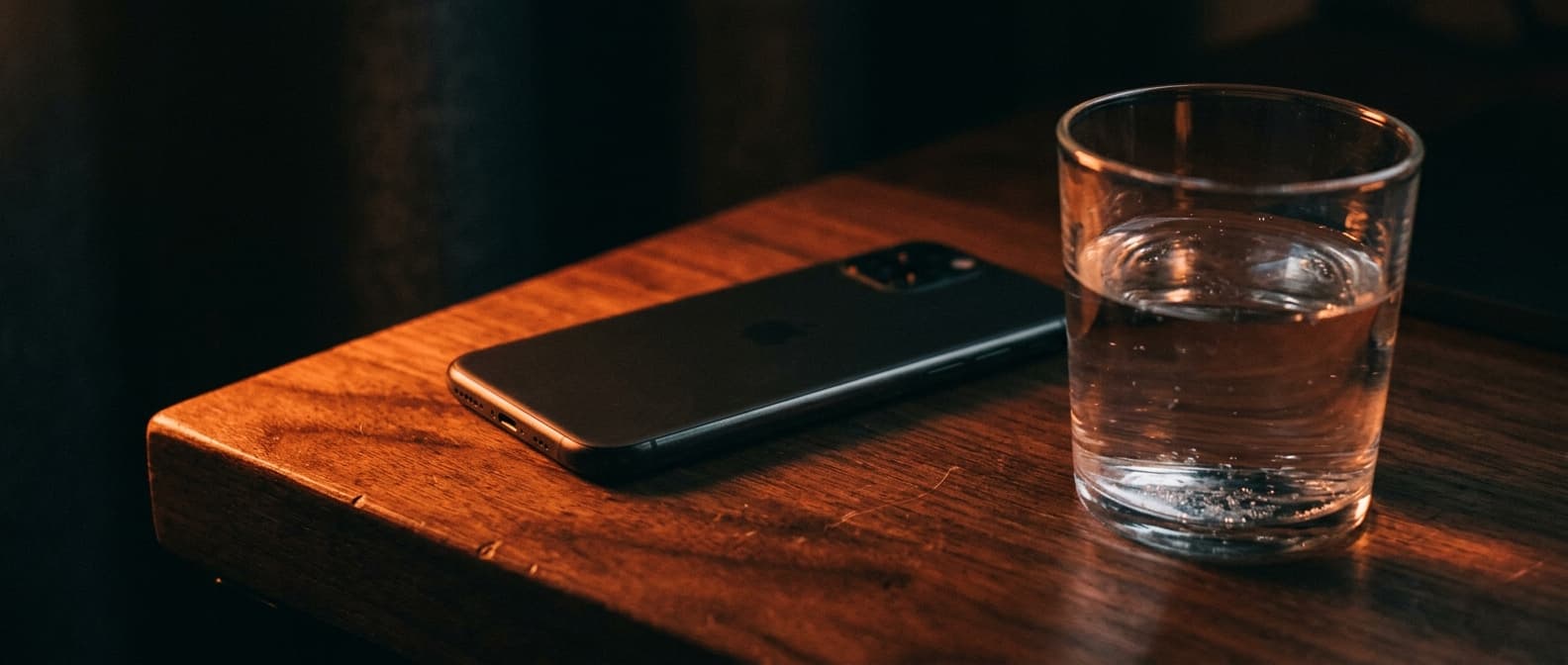 Ein Telefon auf einem dunklen Tisch, von warmem Licht gestreift — der Moment vor dem ehrlichen Gespräch
