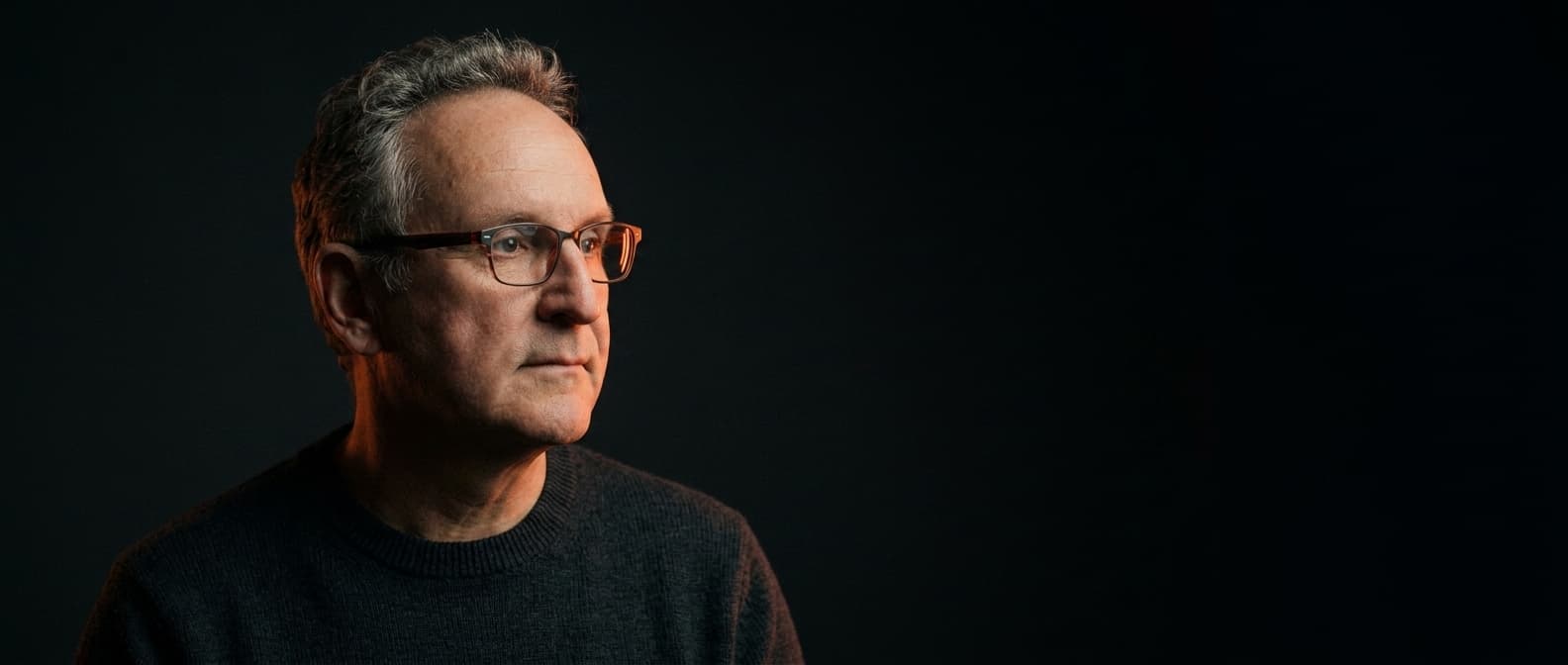 Matthias M.C. Gondorf, nachdenklich, im Dunkeln von warmem Licht gestreift